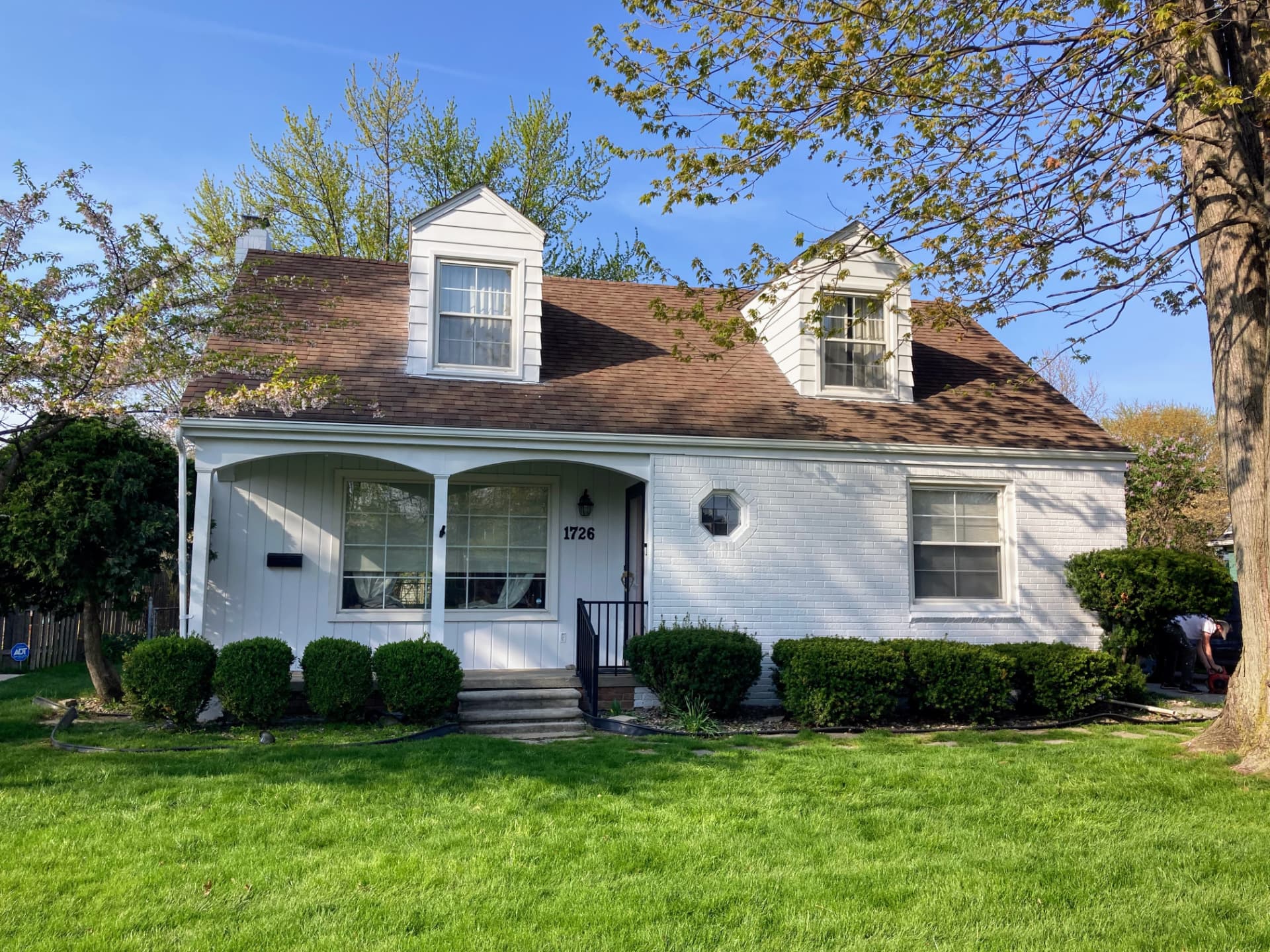 Freshly painted white brick home with brown roof and green lawn